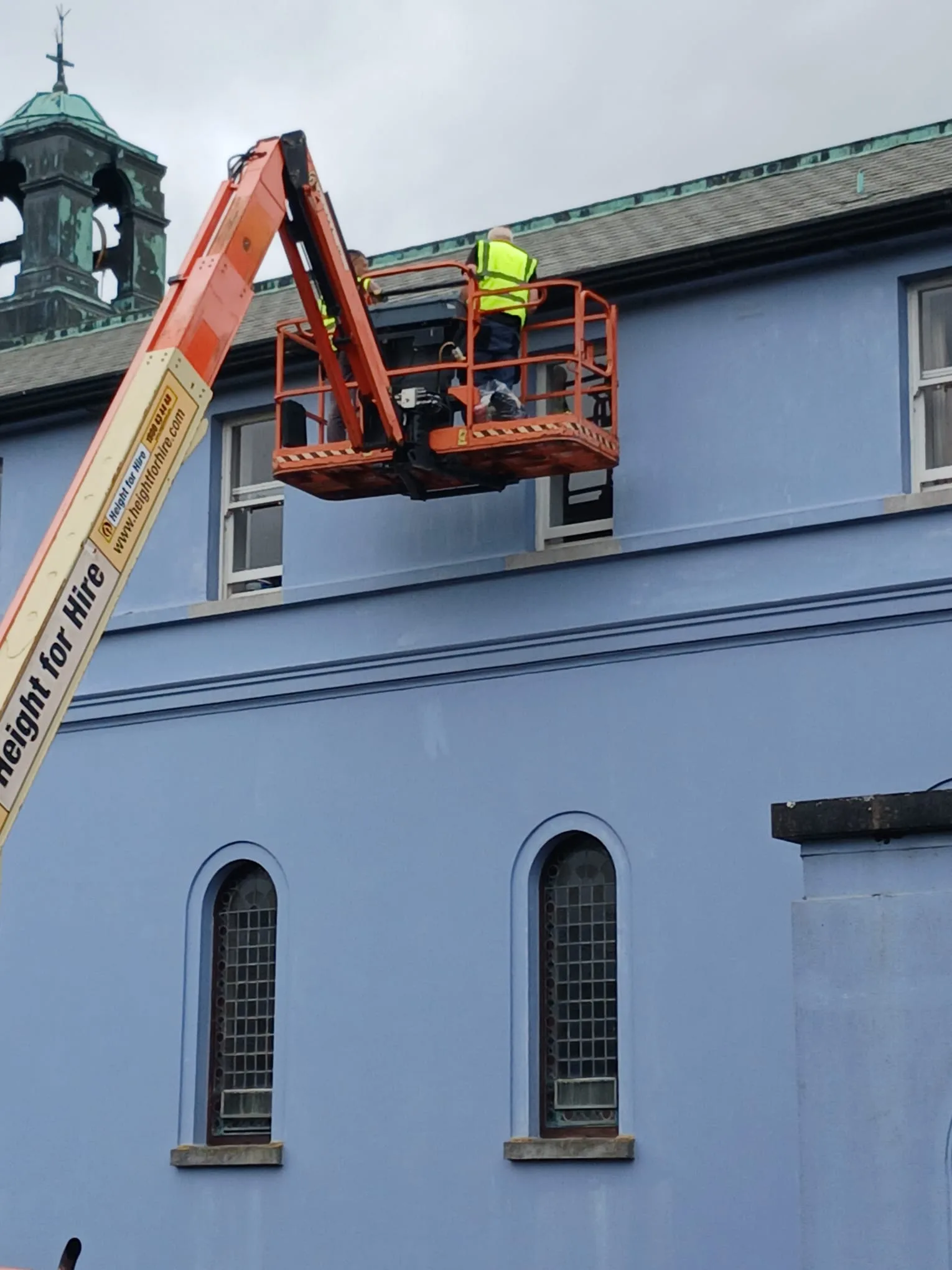 A roofer working at the roofline from a height lift