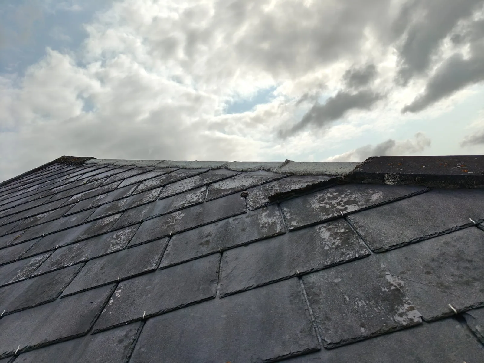 A slate roof with a missing slate after storm damage
